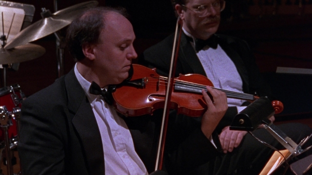 Wide shot frame from Waiting for Guffman — sitting, face, violin