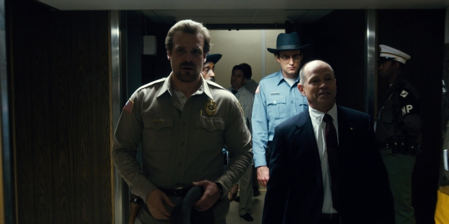 Wide shot frame from Stranger Things — walking, door, uniform