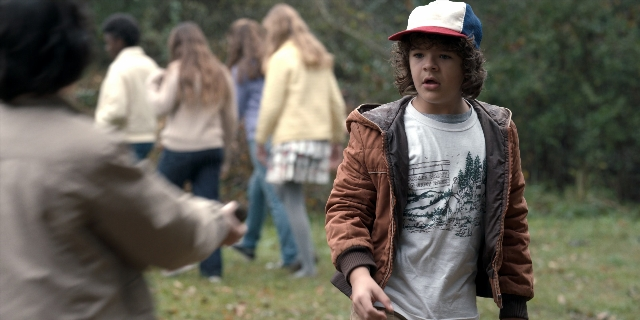 Wide shot frame from Stranger Things — standing, walking, hat
