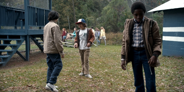 Wide shot frame from Stranger Things — sitting, walking, hand