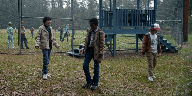 Wide shot frame from Stranger Things — walking, hat, jacket