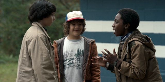 Wide shot frame from Stranger Things — standing, dialogue, hat