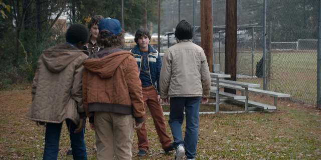 Wide shot frame from Stranger Things — walking, dialogue, hat