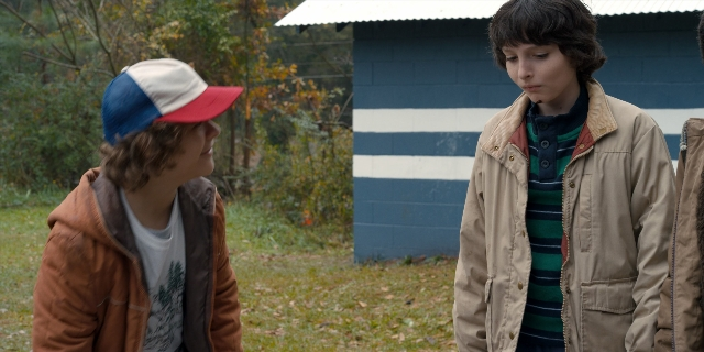 Wide shot frame from Stranger Things — standing, dialogue, hat
