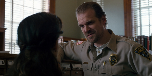 Wide shot frame from Stranger Things — sitting, standing, uniform