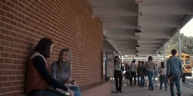 Wide shot frame from Stranger Things — sitting, book, walking