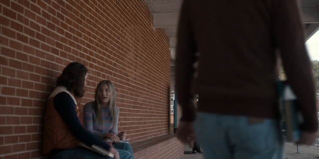Wide shot frame from Stranger Things — sitting, book, walking