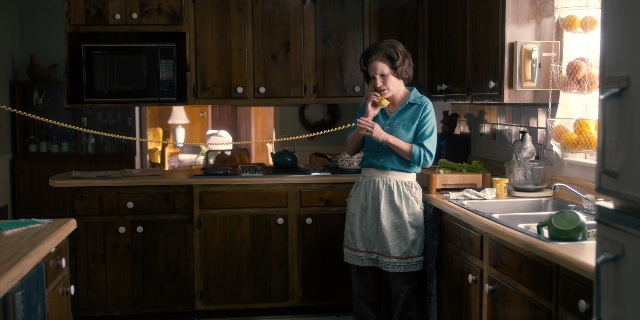 Wide shot frame from Stranger Things — standing, phone, kitchen