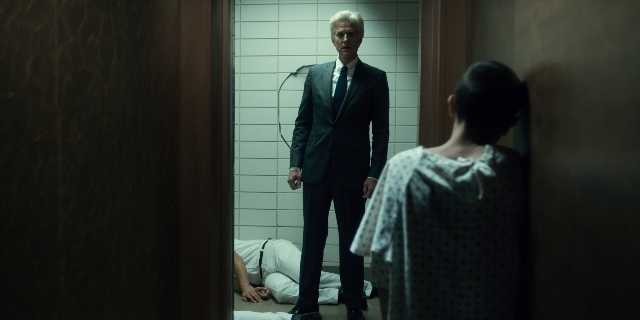 Wide shot frame from Stranger Things — standing, suit, dress