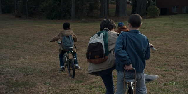 Wide shot frame from Stranger Things — walking, bicycle, person