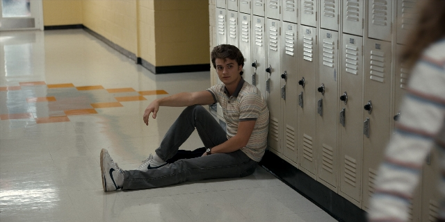 Wide shot frame from Stranger Things — sitting, standing, shirt
