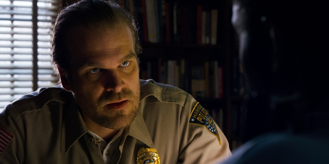 Wide shot frame from Stranger Things — sitting, room, uniform