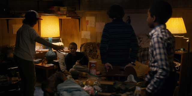Wide shot frame from Stranger Things — standing, room, table
