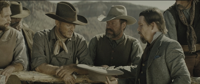 Wide shot frame from The Magnificent Seven — table, hat, person