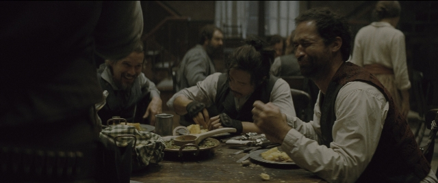 Wide shot frame from The Magnificent Seven — sitting, standing, plate