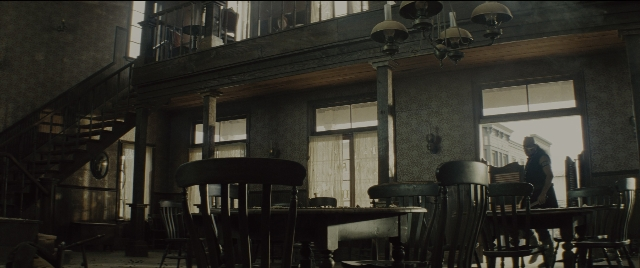 Wide shot frame from The Magnificent Seven — sitting, room, table