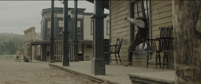 Wide shot frame from The Magnificent Seven — standing, walking, table