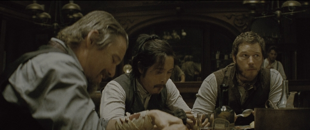 Wide shot frame from The Magnificent Seven — sitting, table, dialogue