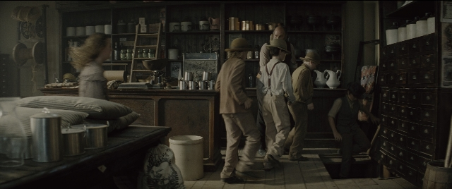 Wide shot frame from The Magnificent Seven — sitting, standing, room