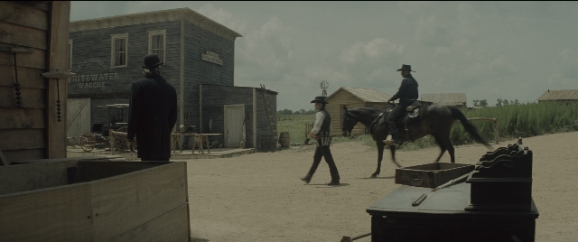 Wide shot frame from The Magnificent Seven — standing, walking, horse