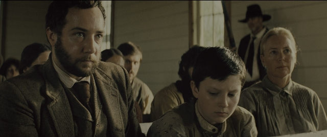 Wide shot frame from The Magnificent Seven — sitting, room, table