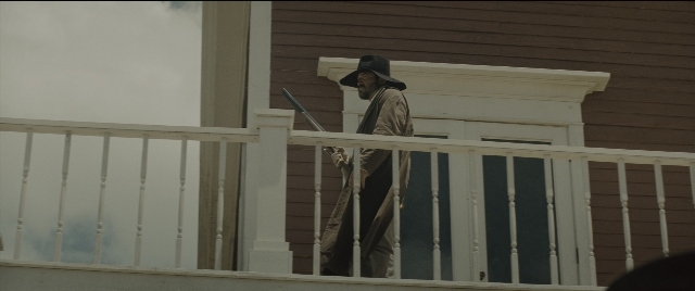 Wide shot frame from The Magnificent Seven — standing, hat, coat
