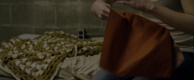 Wide shot frame from 10 Cloverfield Lane — sitting, bed, person