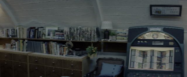 Wide shot frame from 10 Cloverfield Lane — book, room, table
