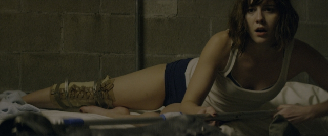 Wide shot frame from 10 Cloverfield Lane — bed, bottle, face