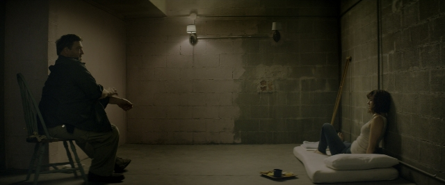 Wide shot frame from 10 Cloverfield Lane — sitting, plate, room
