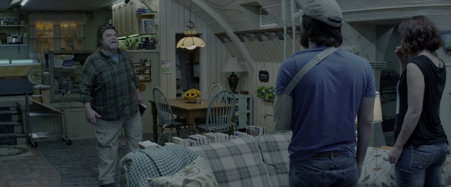 Wide shot frame from 10 Cloverfield Lane — standing, room, table