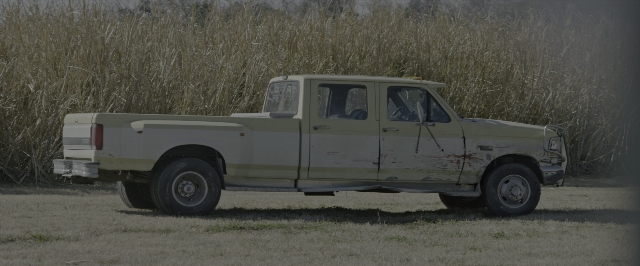 Wide shot frame from 10 Cloverfield Lane — bed, street, truck