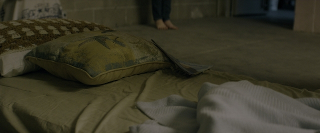 Wide shot frame from 10 Cloverfield Lane — standing, room, bed