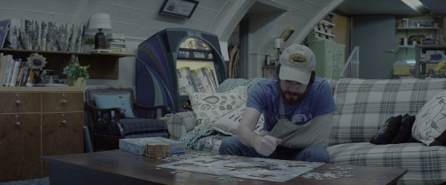 Wide shot frame from 10 Cloverfield Lane — sitting, table, hat