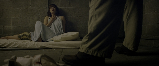Wide shot frame from 10 Cloverfield Lane — sitting, room, bed