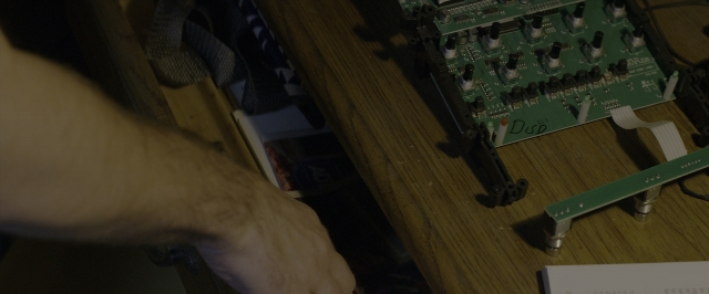 Wide shot frame from 10 Cloverfield Lane — table, hand, person