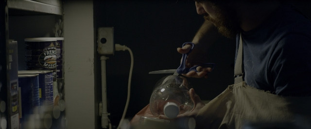 Wide shot frame from 10 Cloverfield Lane — standing, room, table