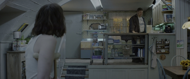 Wide shot frame from 10 Cloverfield Lane — standing, table, dialogue