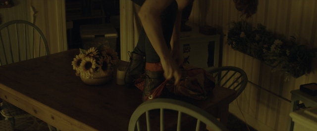 Wide shot frame from 10 Cloverfield Lane — standing, room, table