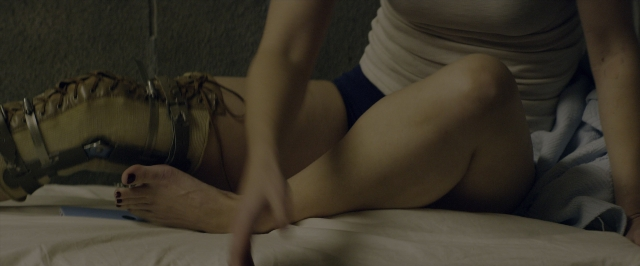 Wide shot frame from 10 Cloverfield Lane — bed, person, footwear