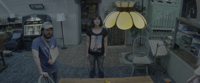 Wide shot frame from 10 Cloverfield Lane — standing, room, table