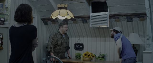 Wide shot frame from 10 Cloverfield Lane — standing, room, table