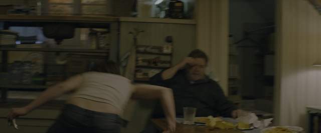 Wide shot frame from 10 Cloverfield Lane — sitting, standing, table