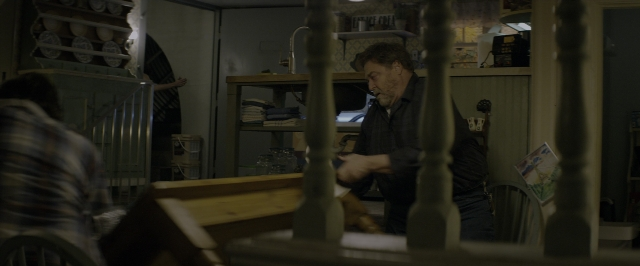 Wide shot frame from 10 Cloverfield Lane — sitting, standing, room