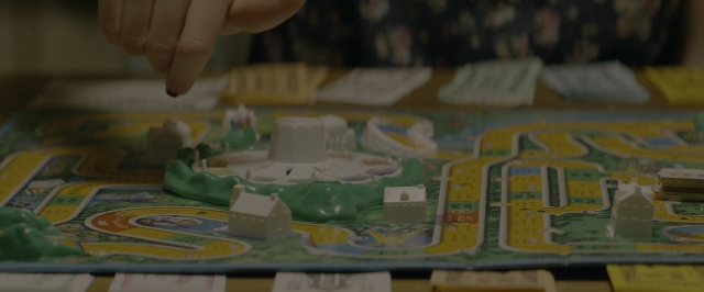 Wide shot frame from 10 Cloverfield Lane — room, table, hand