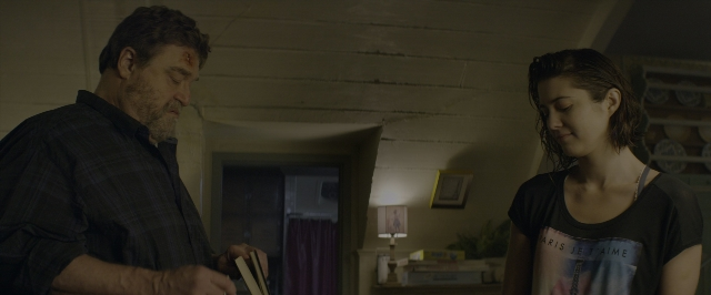 Wide shot frame from 10 Cloverfield Lane — standing, room, table