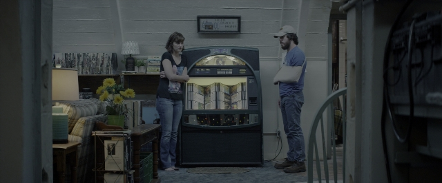 Wide shot frame from 10 Cloverfield Lane — standing, room, table