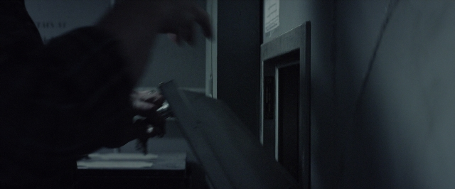 Wide shot frame from 10 Cloverfield Lane — room, table, hand