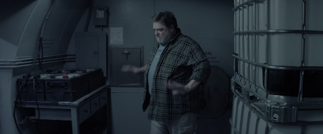 Wide shot frame from 10 Cloverfield Lane — standing, room, table
