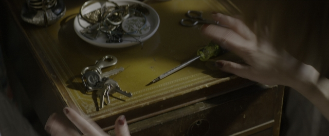 Wide shot frame from 10 Cloverfield Lane — plate, table, hand